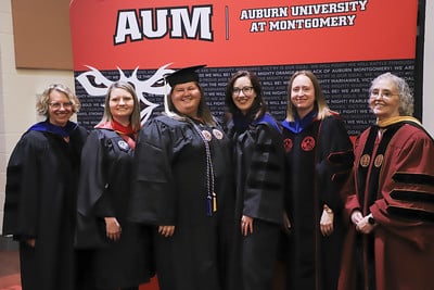 Graduates and faculty in regalia posing at Auburn University at Montgomery event.