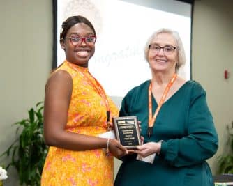 Two women smiling and holding an award plaque at an Auburn University at Montgomery event.
