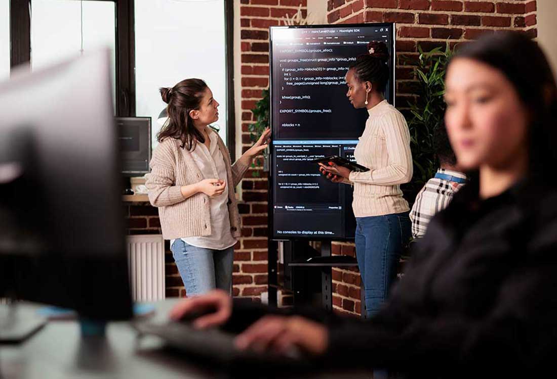 AUM students collaborating on code in a computer lab, discussing code on a display at Auburn University at Montgomery