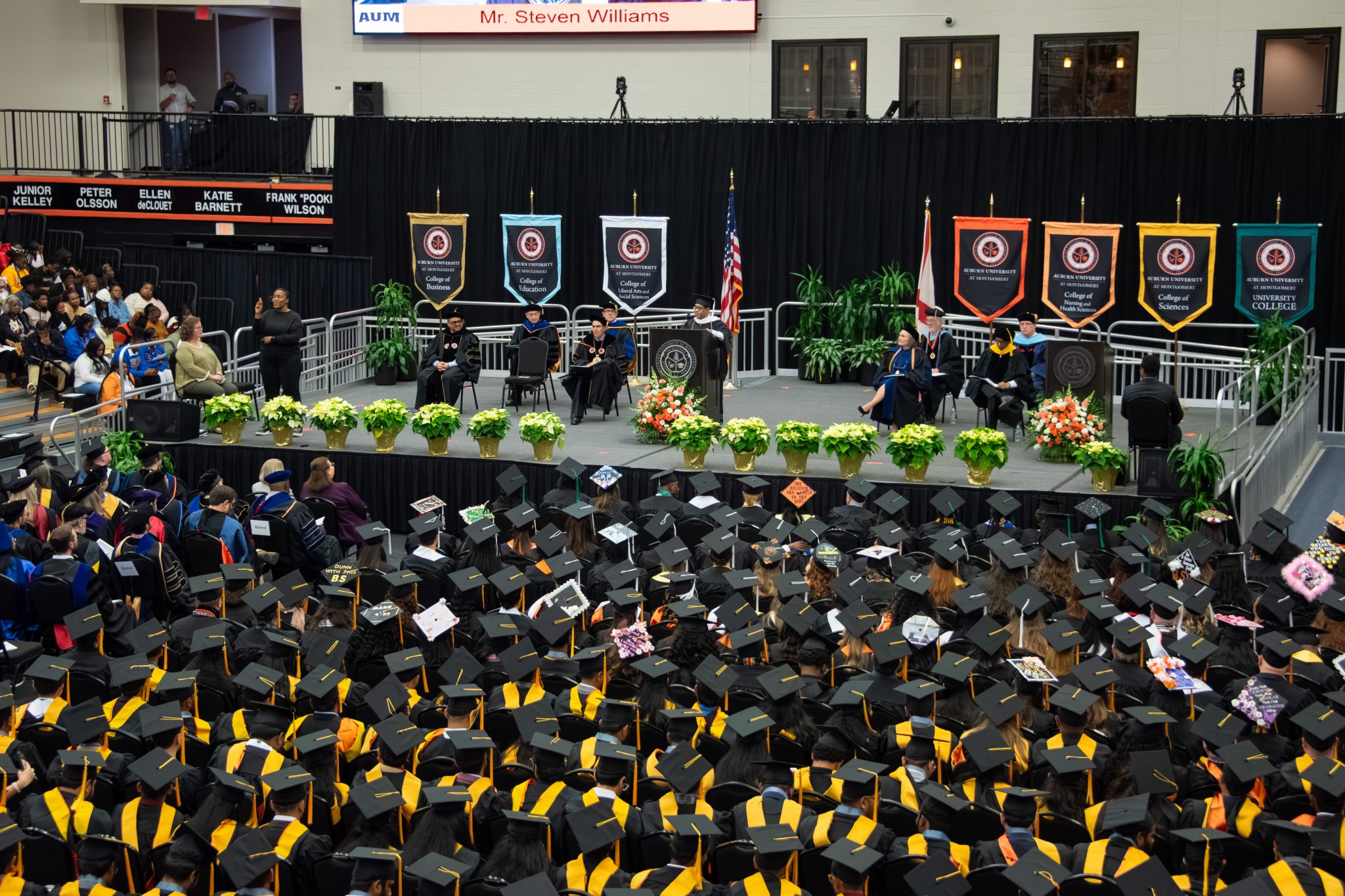 Graduation ceremony at Auburn University at Montgomery with students in caps and gowns and faculty on stage.