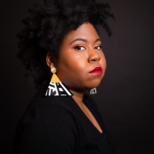 A Person Poses With Colorful Geometric Earrings Against A Dark Background, Showcasing Modern Artistic Style.