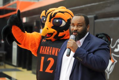 Aubie the Warhawk mascot and a person speaking at Auburn University at Montgomery event.