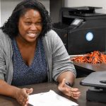 Auburn University at Montgomery advisor meets with a student in an office, discussing paperwork at a desk.