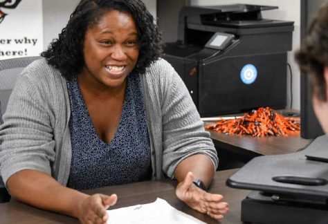 Auburn University at Montgomery advisor meets with a student in an office, discussing paperwork at a desk.