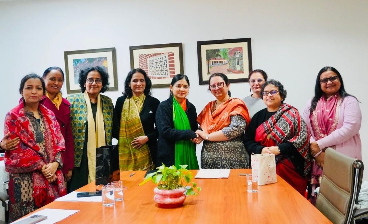 Auburn University at Montgomery staff meeting—group of women around a table, two shaking hands, partnership discussion