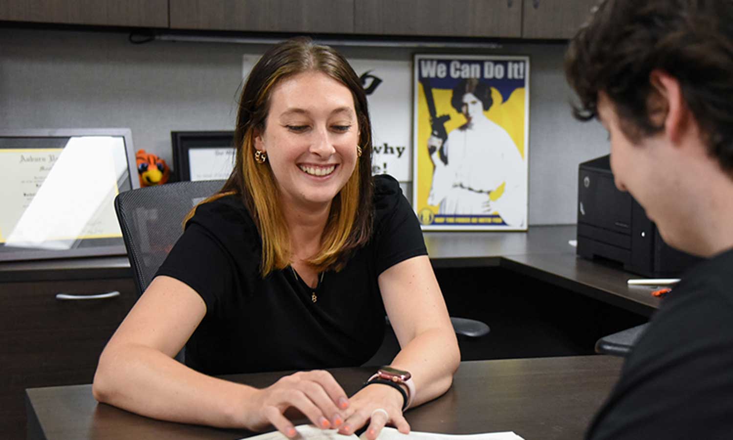 Auburn University at Montgomery advisor smiles while meeting with a student in an office during academic advising