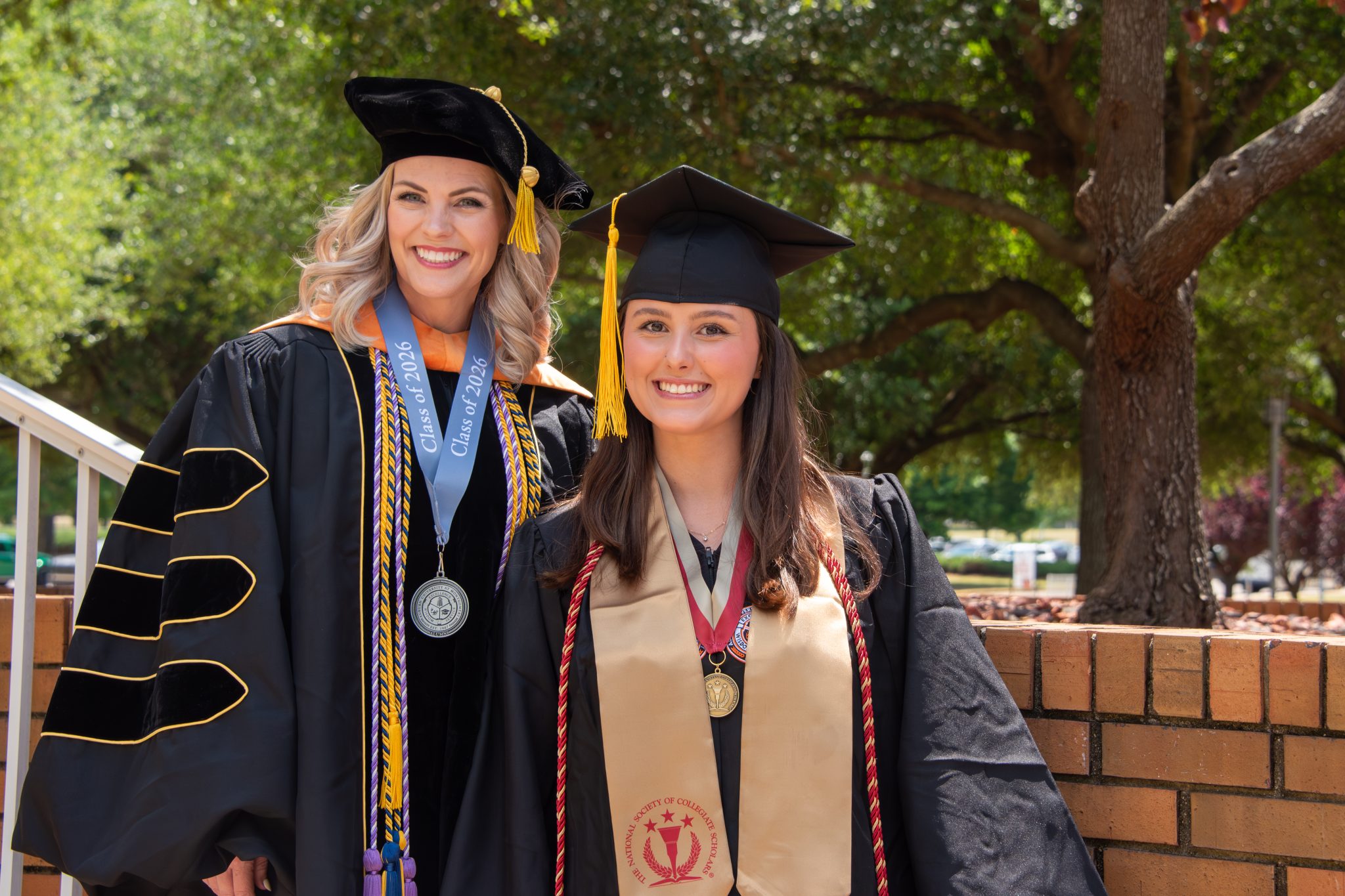 Auburn University at Montgomery graduates in caps and gowns smile on campus during commencement, Class of 2026