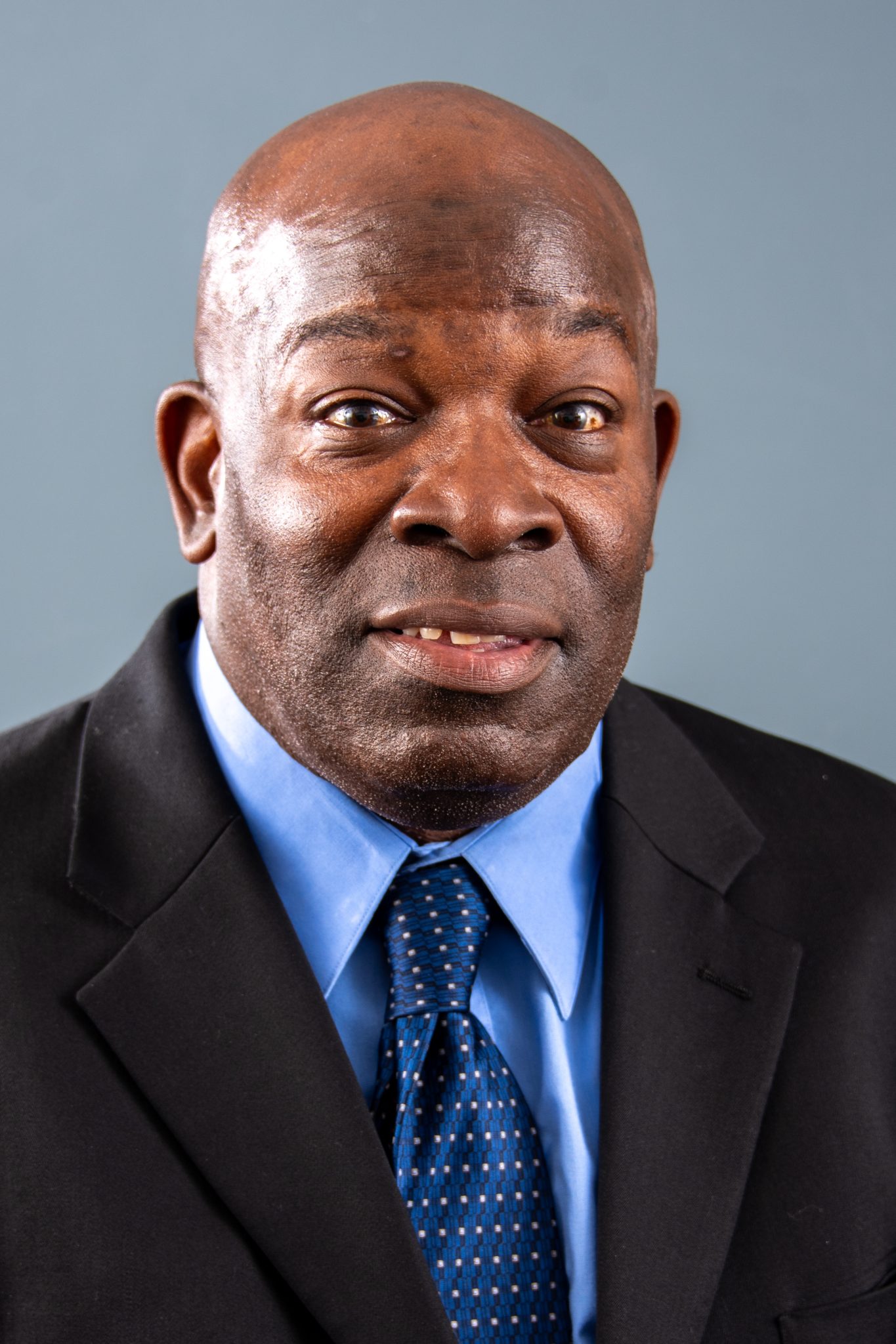 Auburn University at Montgomery professional headshot of a man in a suit and blue tie on a gray background.