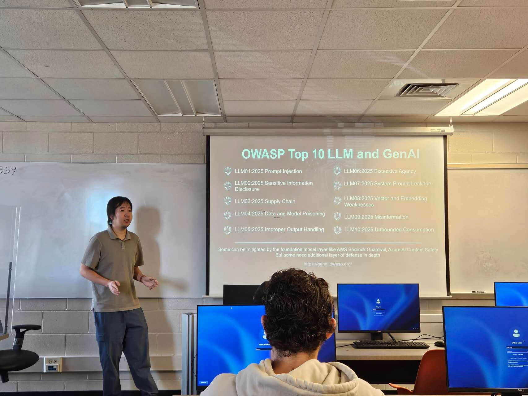 Auburn University at Montgomery classroom lecture on OWASP Top 10 LLM and GenAI, a person presenting to students with screens