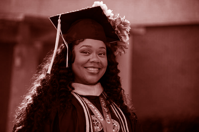 Auburn University at Montgomery graduate smiles in cap and gown at commencement ceremony on campus