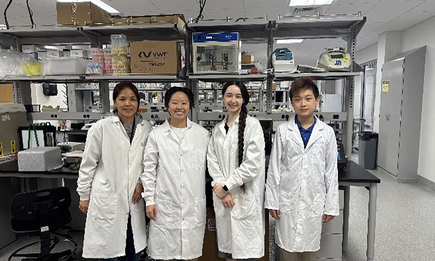 Auburn University at Montgomery students in lab coats pose in a campus science research lab.