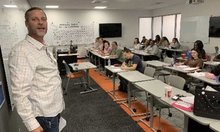 Auburn University at Montgomery classroom with a professor leading a lecture as students take notes in a modern room