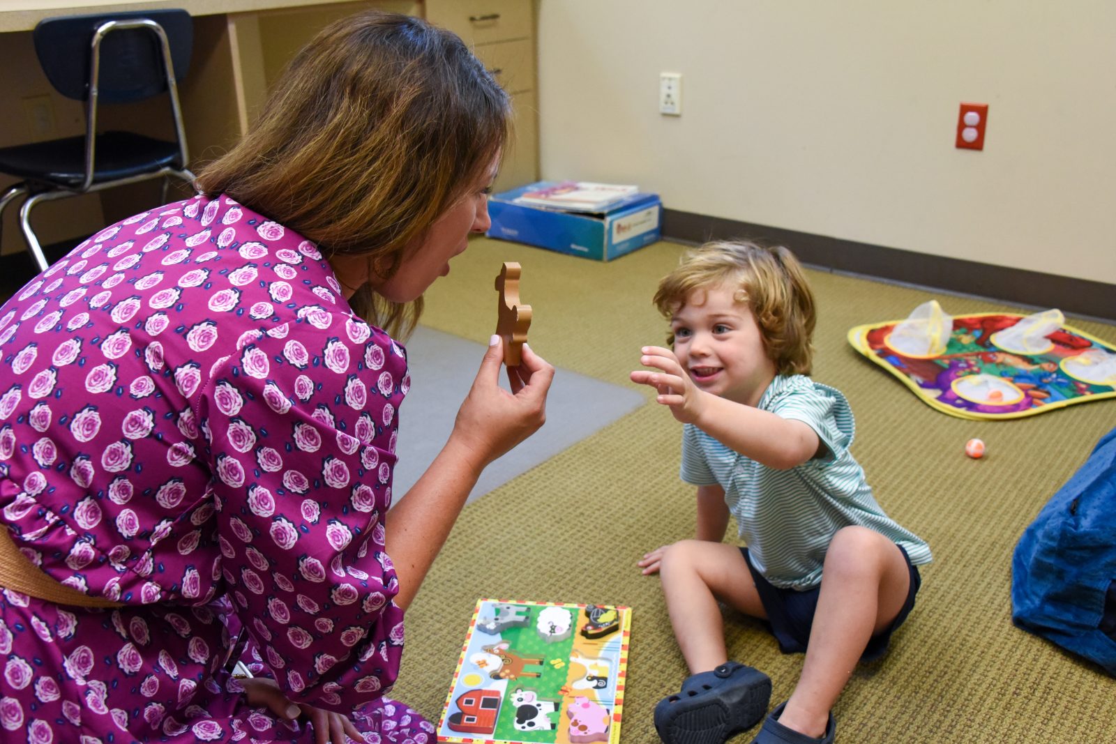 Auburn University at Montgomery education: a woman guides a child with a farm puzzle during a learning session