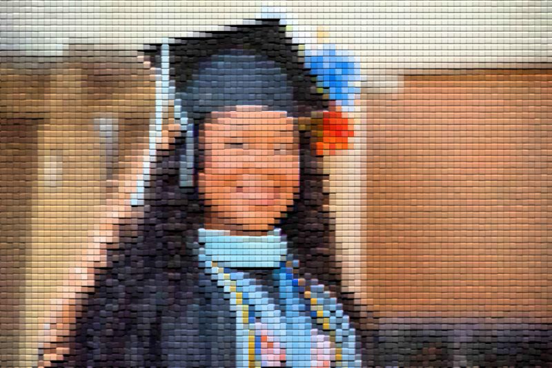 Auburn University at Montgomery graduate smiling in cap and gown with honor cords at commencement ceremony