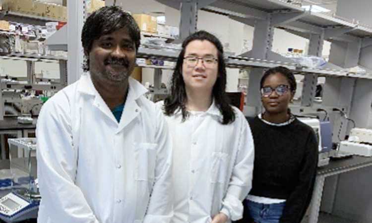 Auburn University at Montgomery students, two in lab coats, standing in a campus science research laboratory.