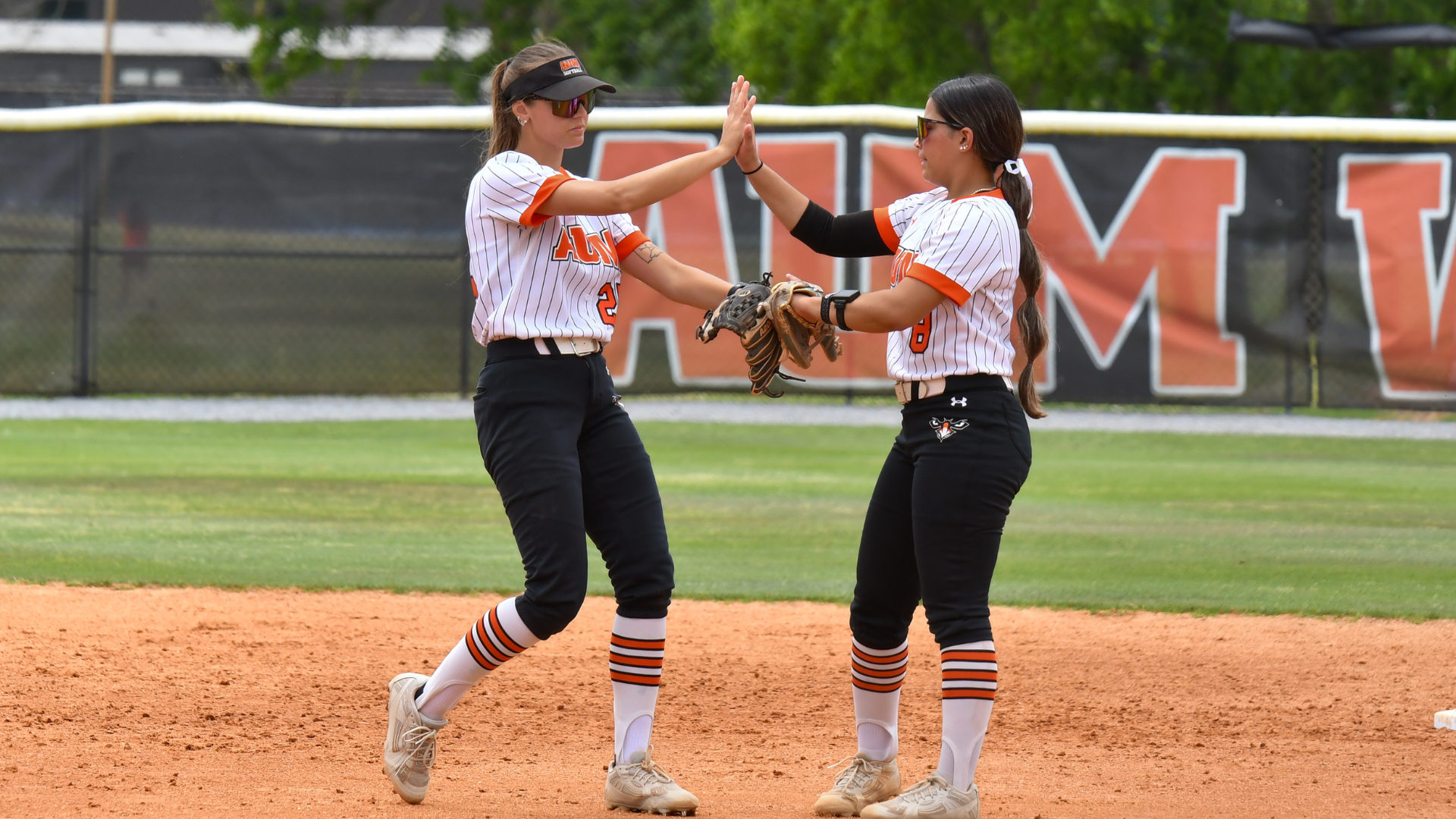 AUM Warhawks softball teammates high-five after a play at Auburn University at Montgomery