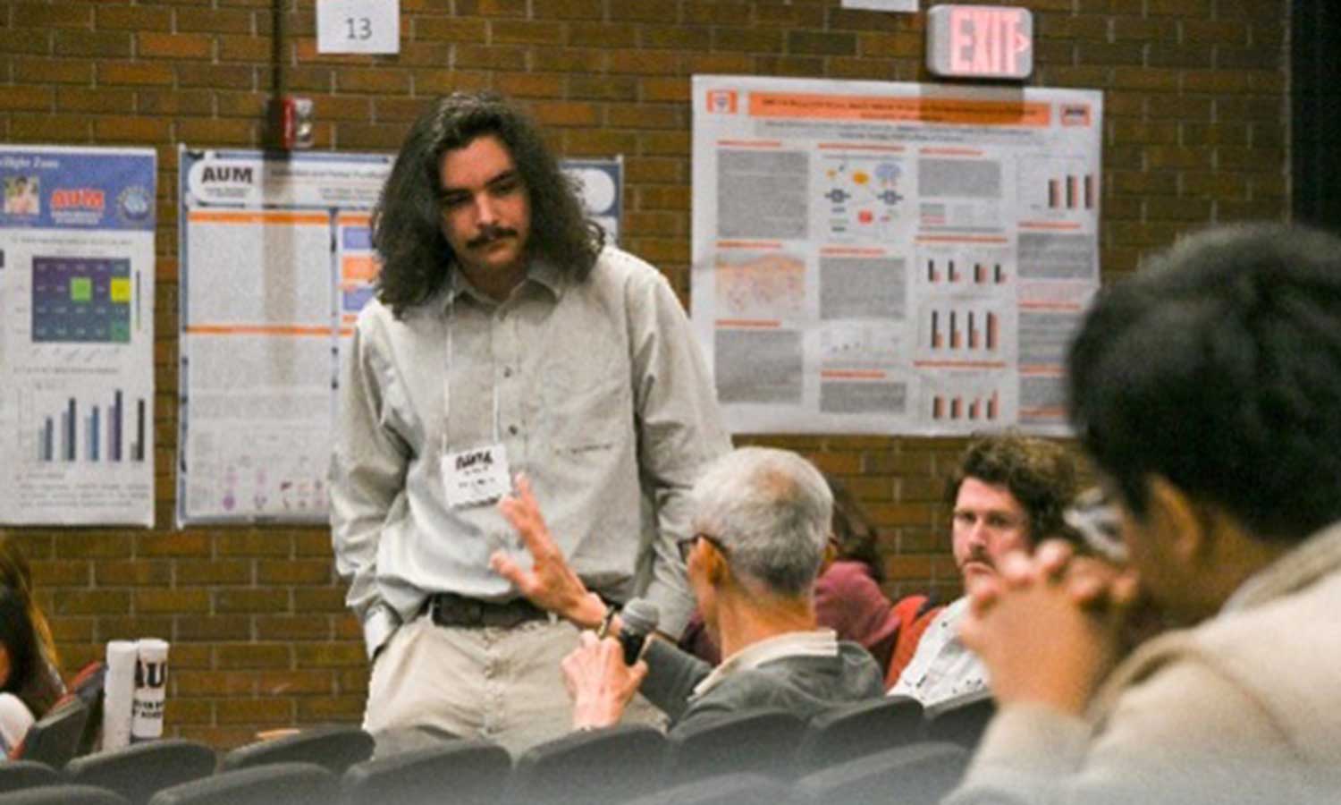 Auburn University at Montgomery student takes an audience question during a campus research poster session.