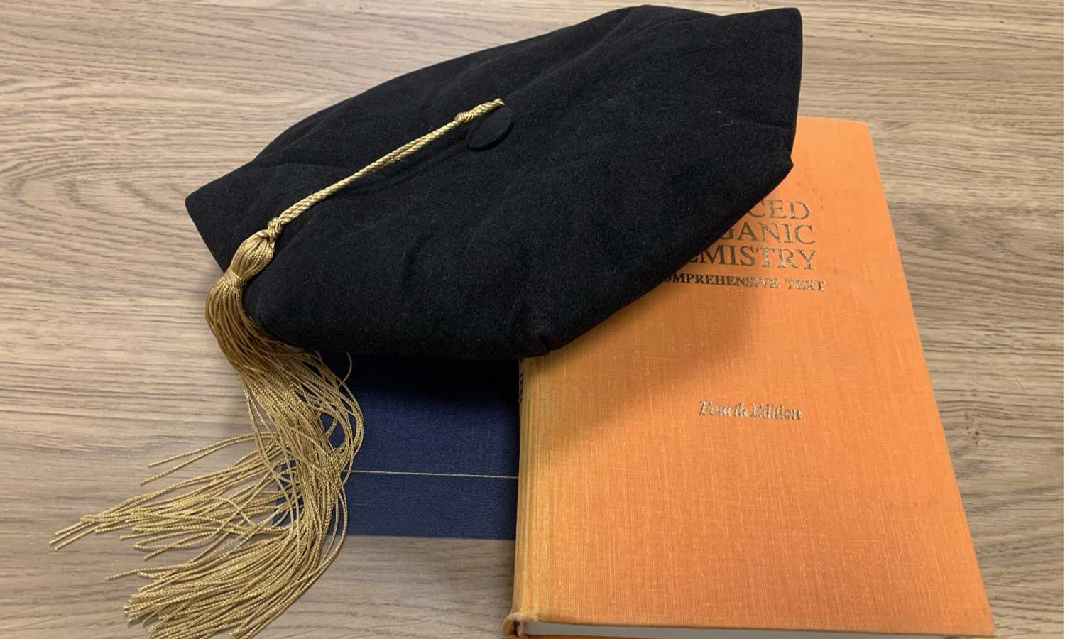 Doctoral tam with gold tassel on chemistry textbooks at Auburn University at Montgomery, celebrating graduate success