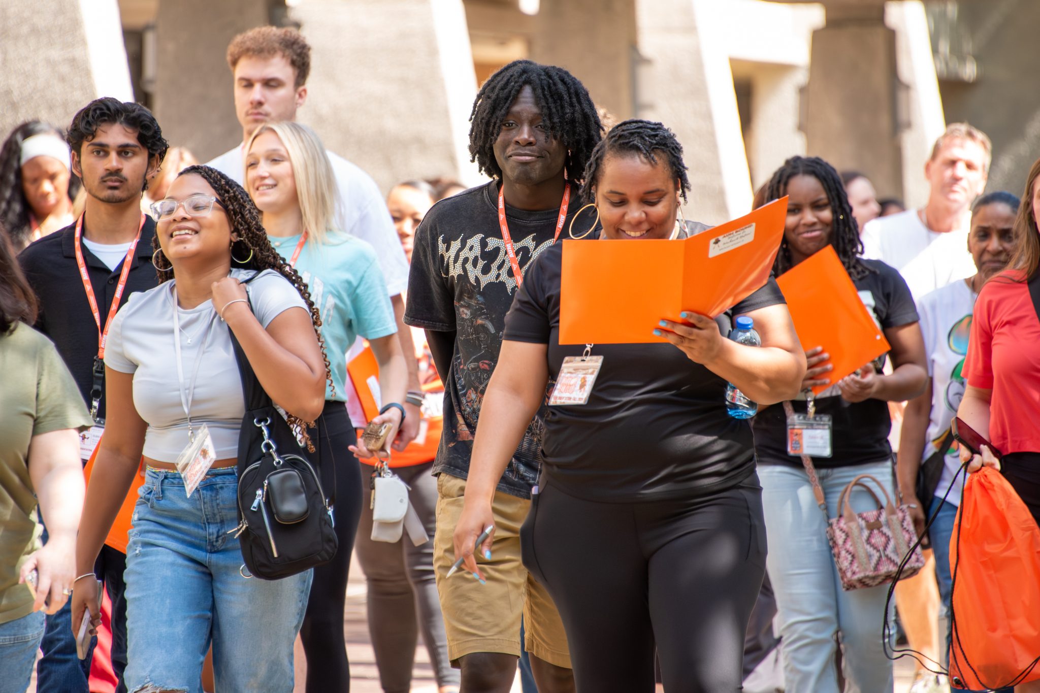 Auburn University at Montgomery students at orientation walking across campus with orange folders