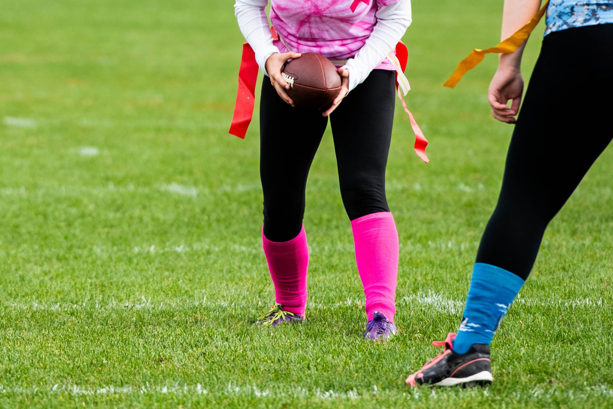 AUM students play flag football on a field outside.