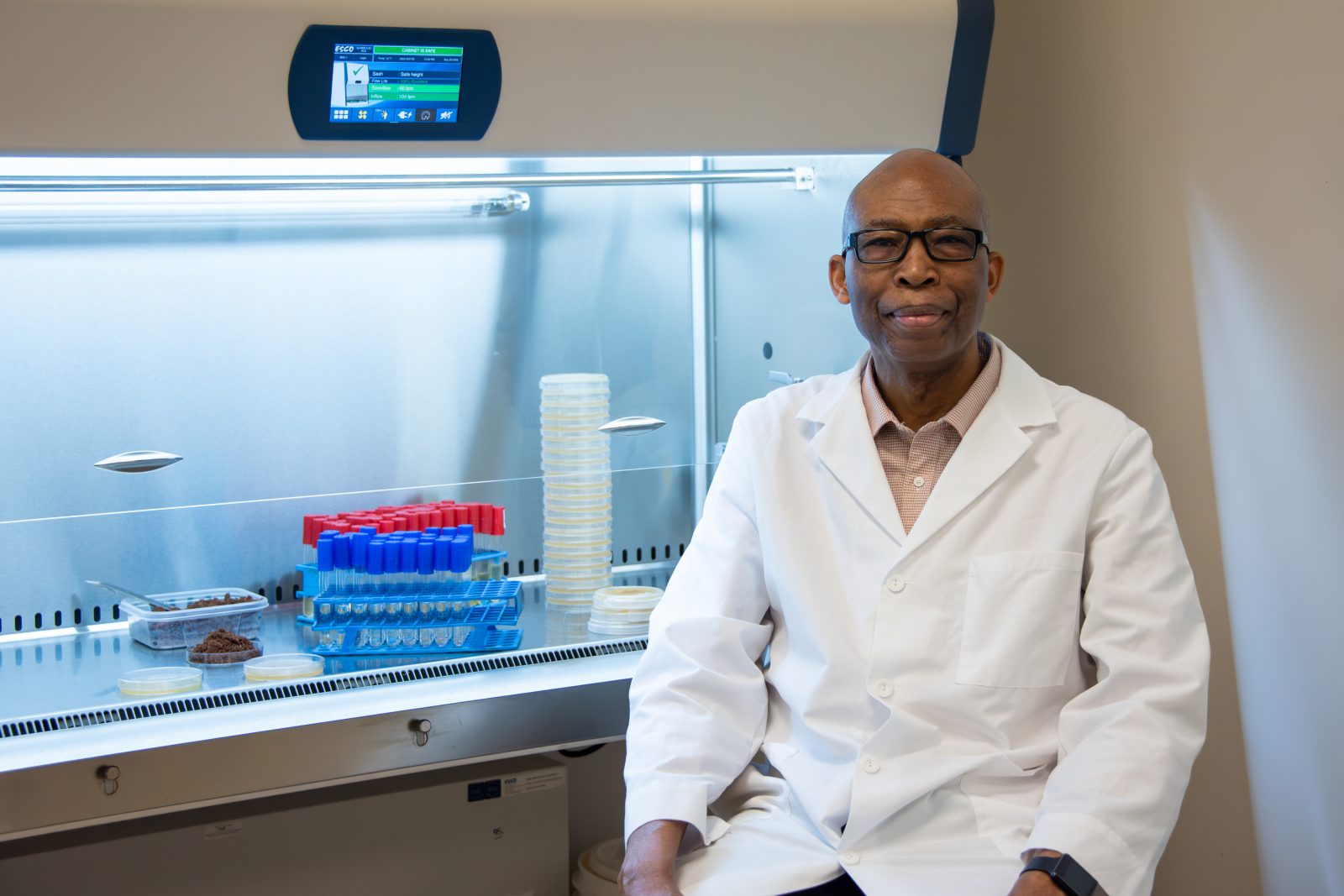 AUM researcher in lab coat in biosafety cabinet with test tubes and petri dishes at Auburn University at Montgomery