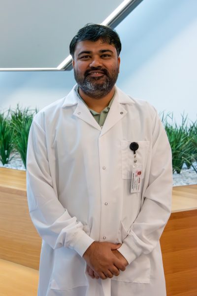 Auburn University at Montgomery researcher in a lab coat smiles in campus science building