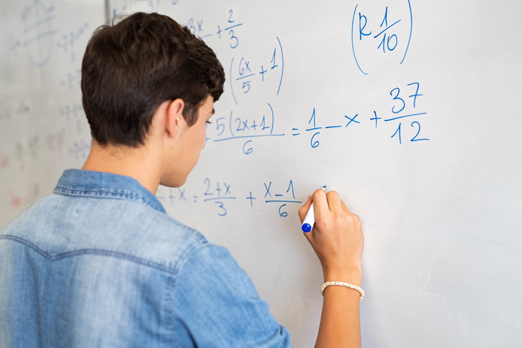 Auburn University at Montgomery student solving algebra equations on a whiteboard in math class.