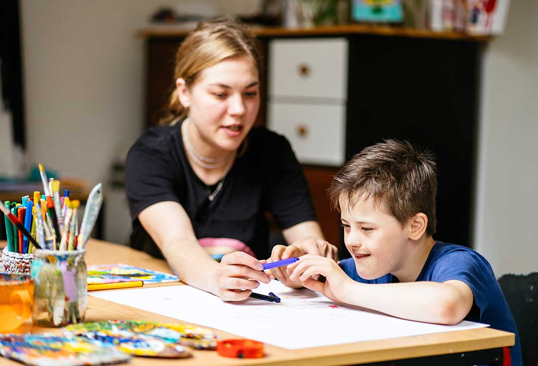 Auburn University at Montgomery education student helping a child draw with markers at a classroom table
