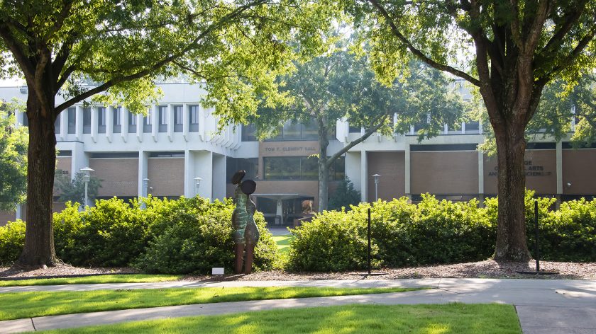 Tom F. Clement Hall At Auburn University At Montgomery Framed By Trees, Sculpture, And Green Lawn On A Sunny Day