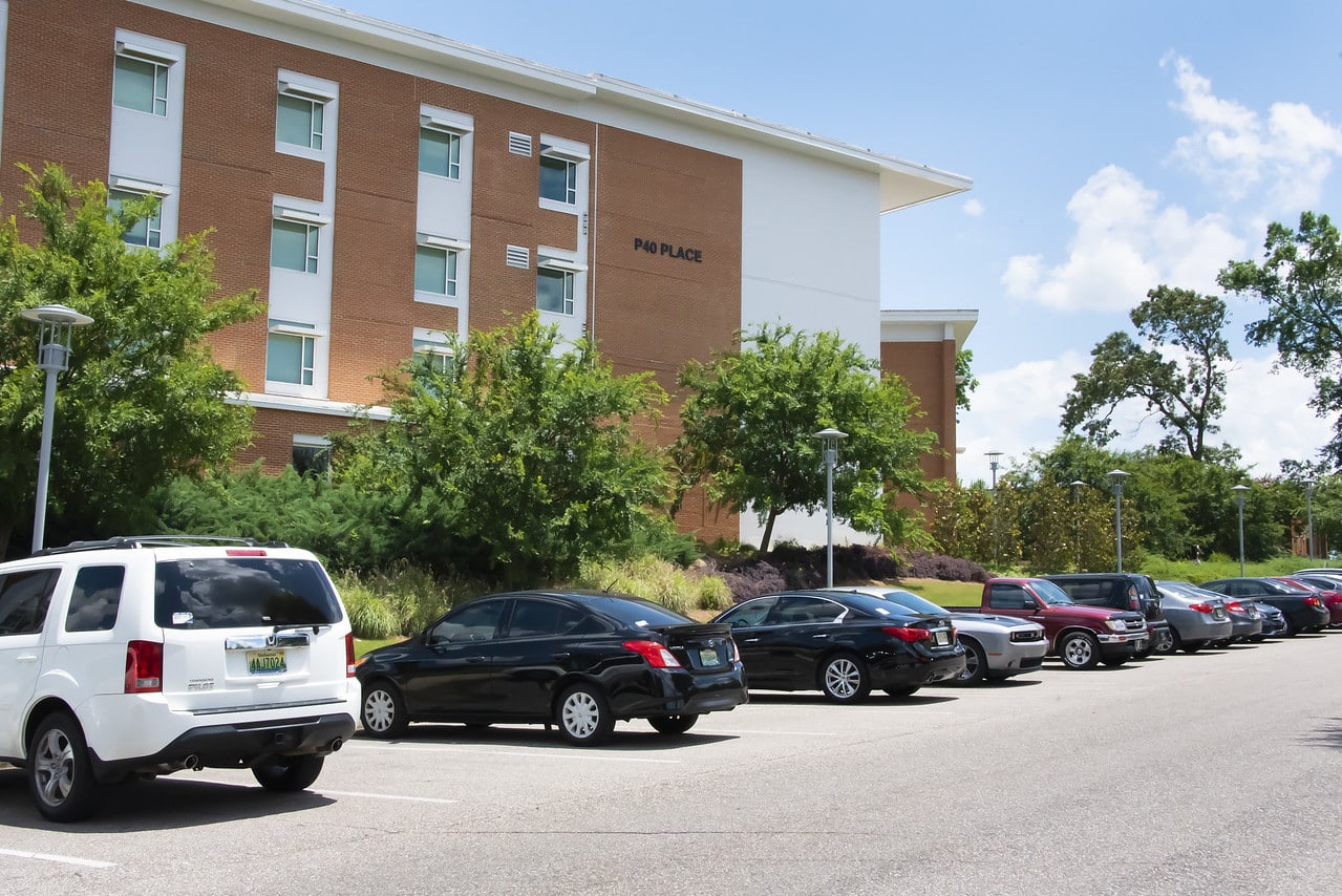 Auburn University at Montgomery P40 Place residence hall with campus parking lot and cars on a sunny day
