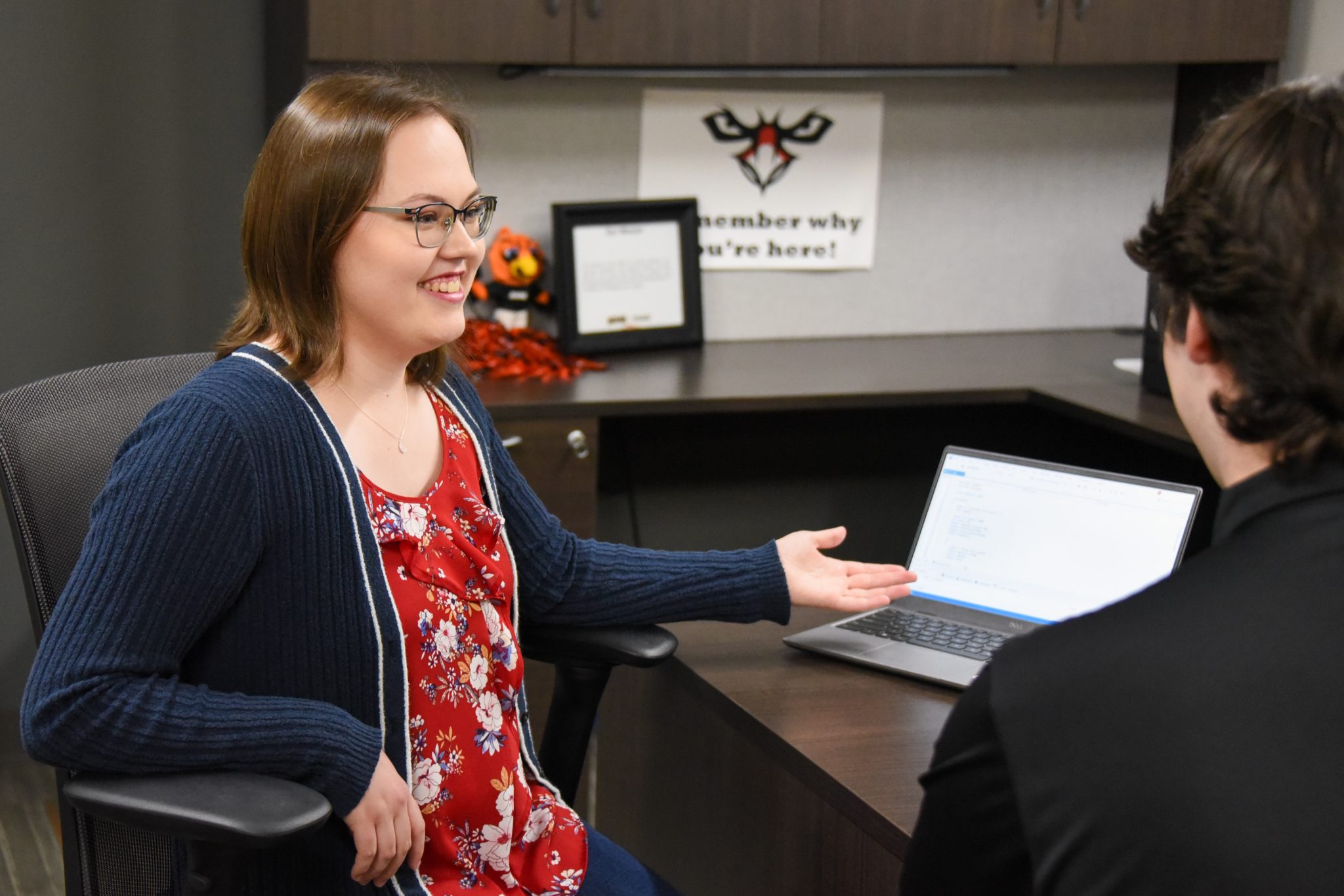 AUM student meets with advisor in campus office, smiling as they review notes on a laptop at Auburn University at Montgomery.