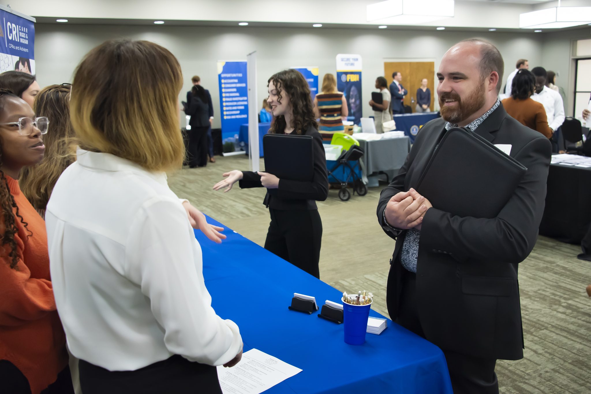 Auburn University at Montgomery students meet with employers at a campus career fair table, discussing opportunities.