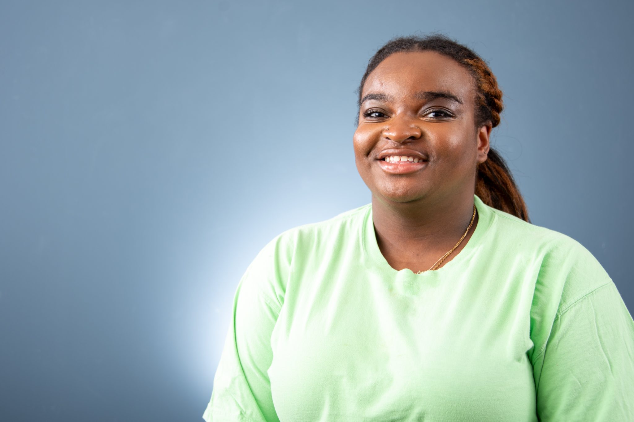 Auburn University at Montgomery student smiling in a light green shirt, studio portrait on blue background