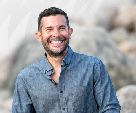 Smiling man in blue shirt outdoors with rocks, representing Auburn University at Montgomery community.