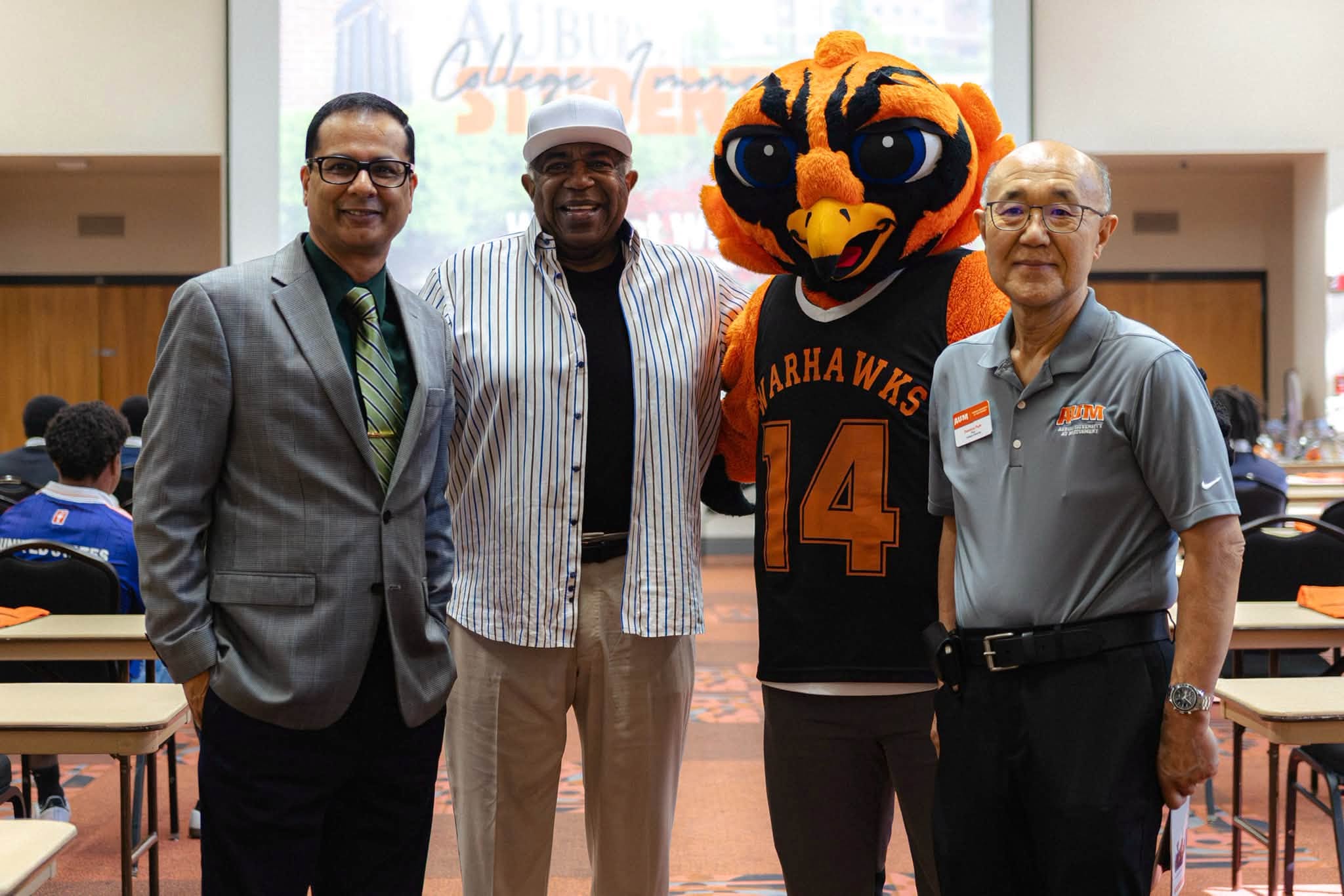AUM Warhawks mascot poses with three men at a campus event at Auburn University at Montgomery.
