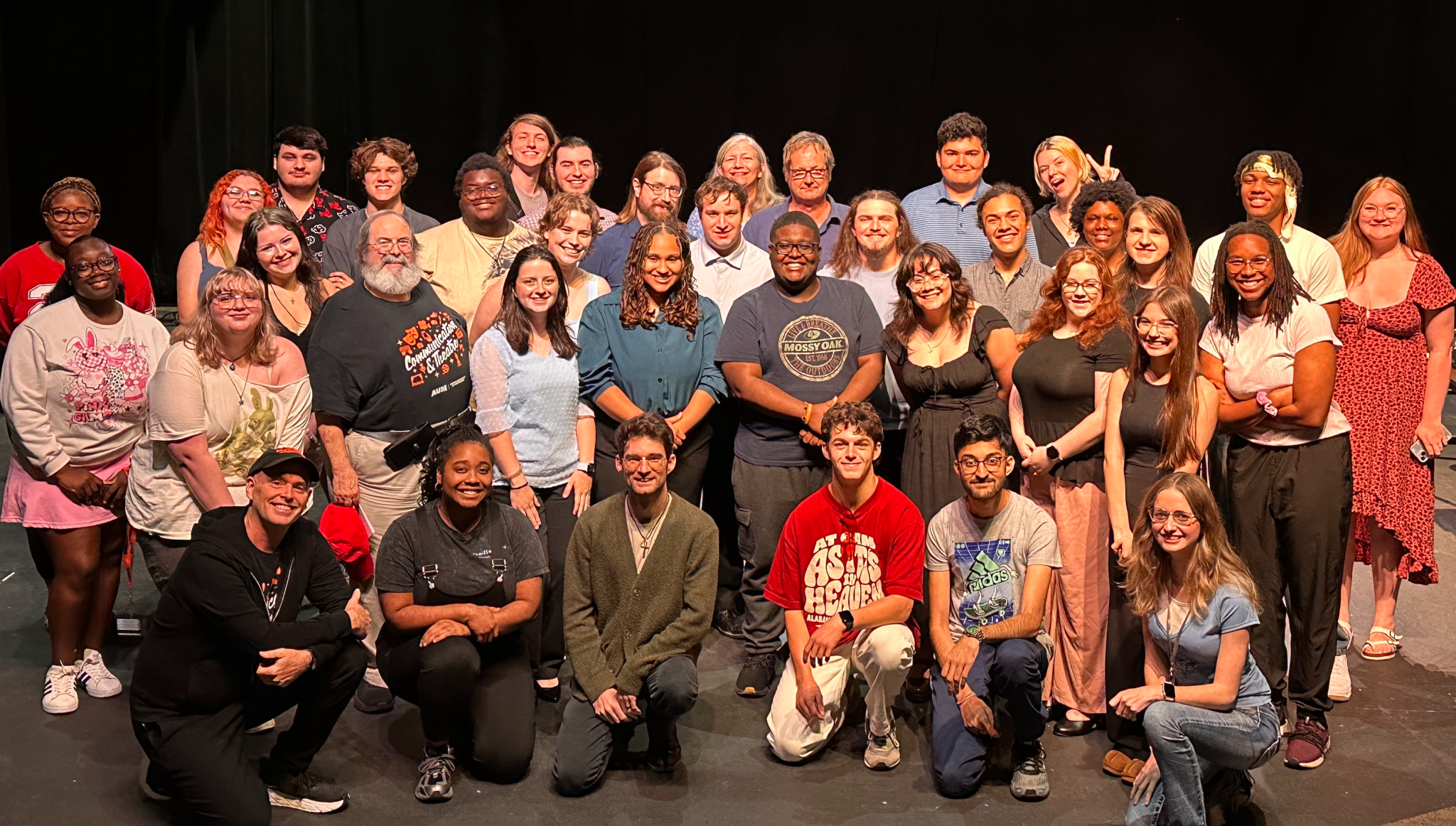 AUM students pose on theater stage after campus event, group portrait at Auburn University at Montgomery