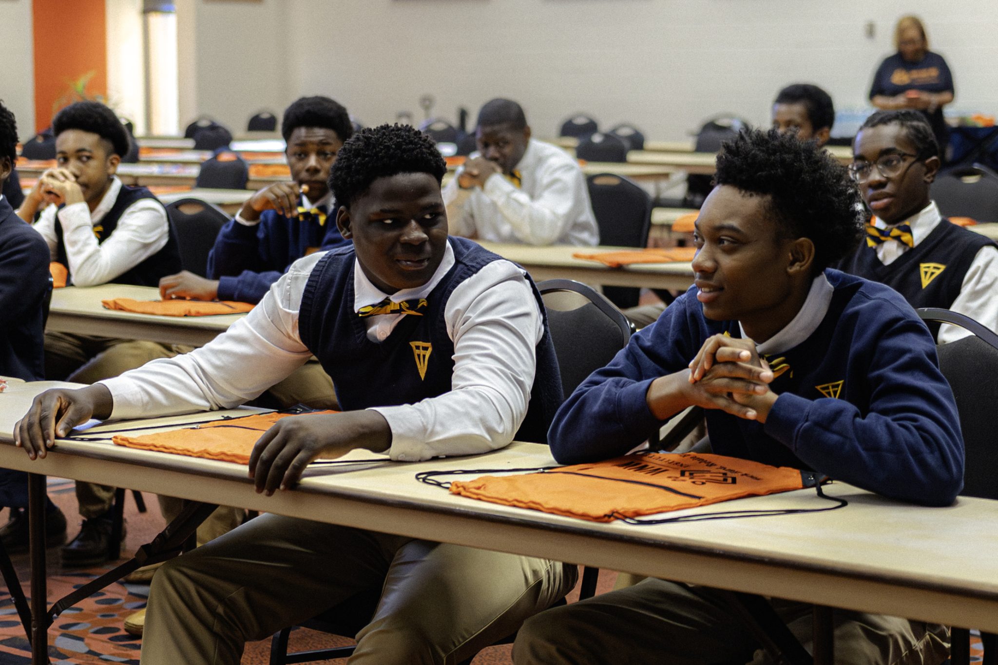 Auburn University at Montgomery students in a classroom, talking during a workshop with orange AUM bags on tables