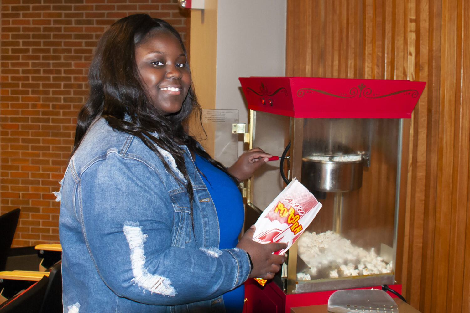 Auburn University At Montgomery Student Makes Popcorn At Campus Event, Smiling By Red Popcorn Machine