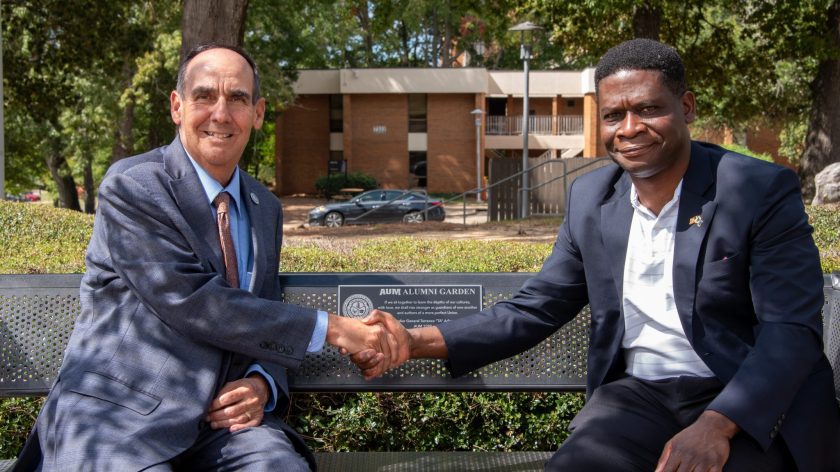 Two Men In Suits Shake Hands On An AUM Alumni Garden Bench At Auburn University At Montgomery Campus.