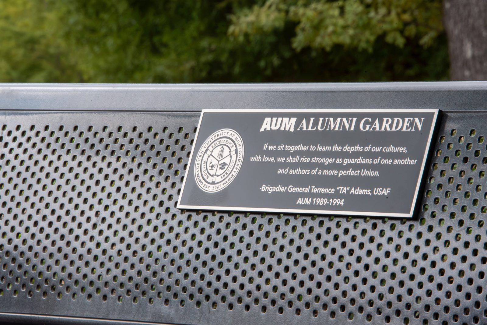 AUM Alumni Garden bench plaque at Auburn University at Montgomery with campus seal and dedication quote