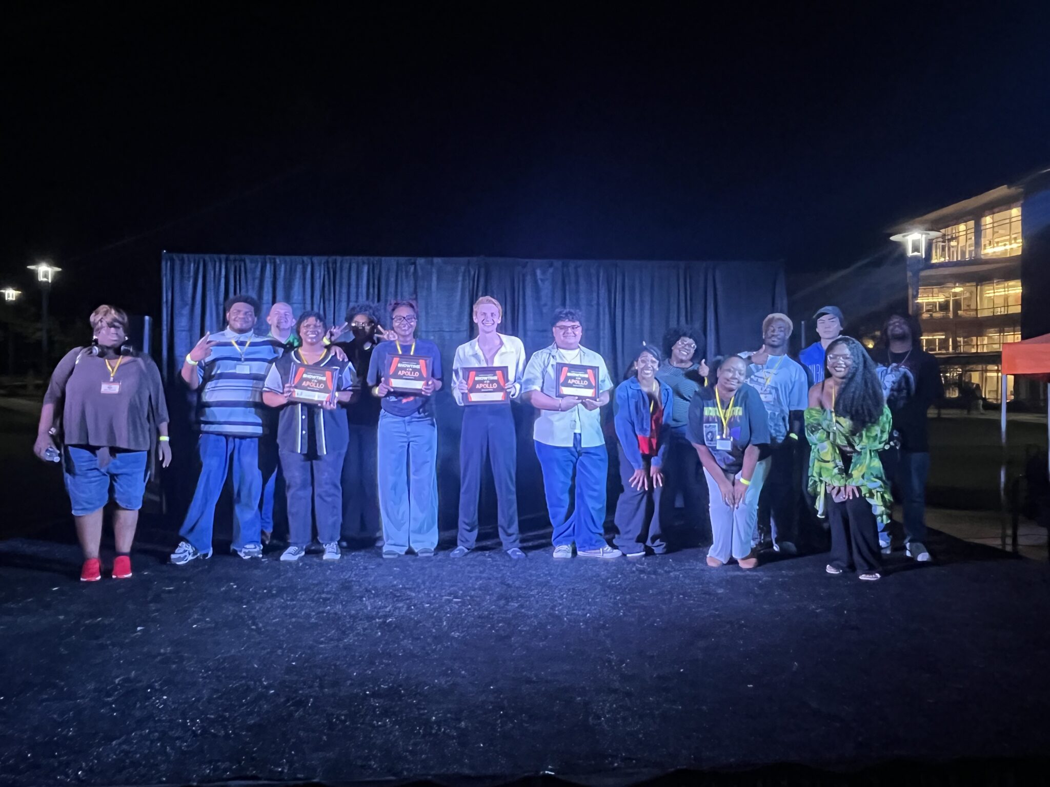 Auburn University at Montgomery students on outdoor stage at night, holding Apollo awards after a campus talent show.
