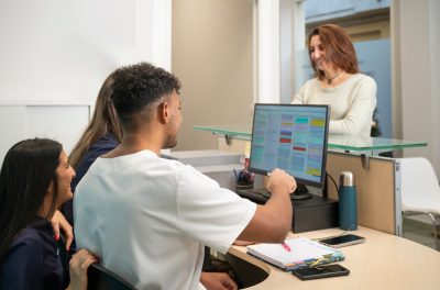 Auburn University at Montgomery students manage clinic front desk, scheduling and helping a person at check-in.
