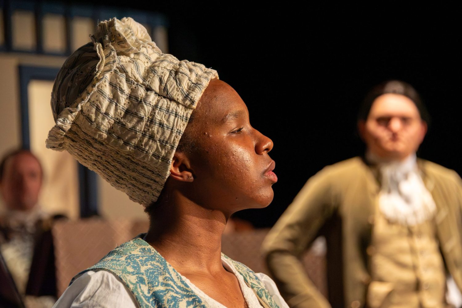 Auburn University At Montgomery Theatre Scene With A Person In Colonial Costume, Side Profile, Actors Blurred.