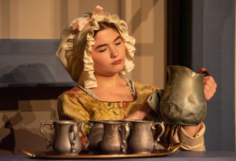 Auburn University at Montgomery theatre: a person in period costume polishing a pewter pitcher and mugs on stage